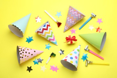 Photo of Beautiful party hats and other festive decor on yellow background, flat lay