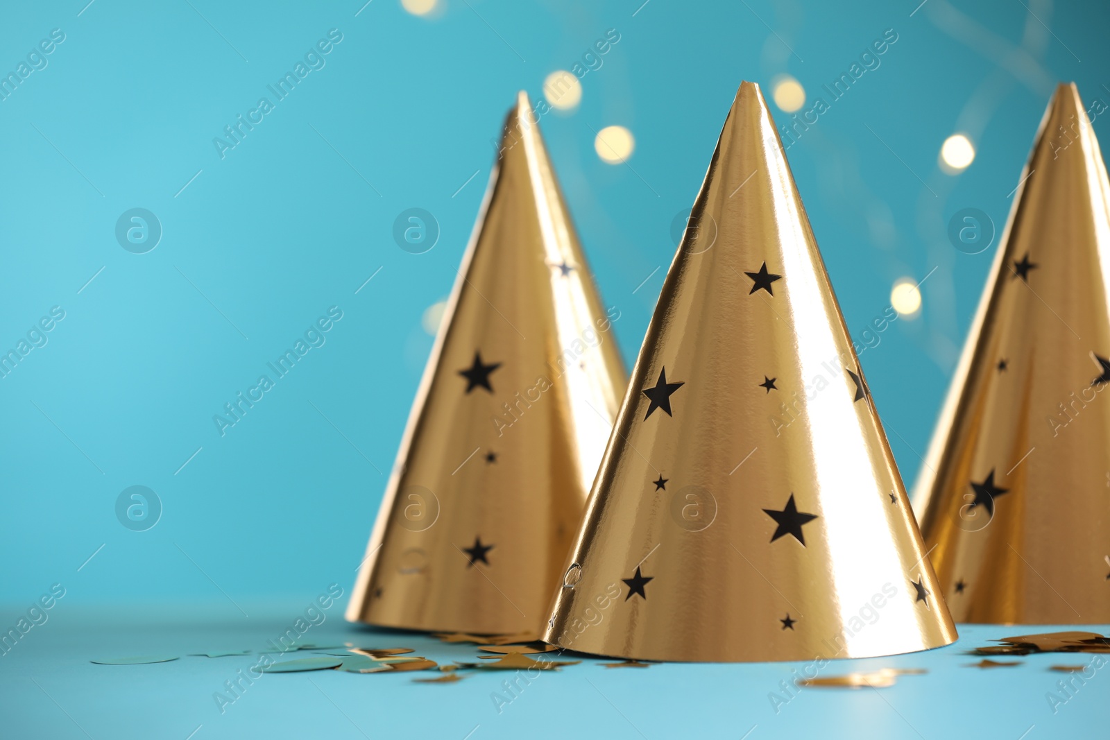 Beautiful party hats and confetti on light blue background, space for text. Bokeh effect Photo of Beautiful party hats and confetti on light blue background, space for text. Bokeh effect