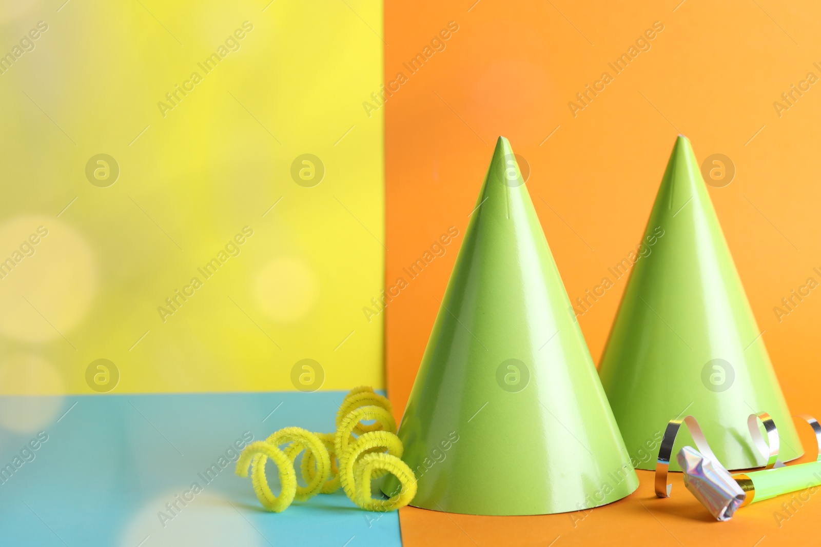 Beautiful party hats, streamers and blower on color background, space for text Photo of Beautiful party hats, streamers and blower on color background, space for text