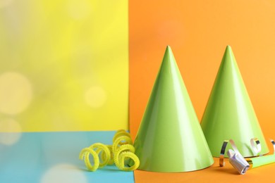 Photo of Beautiful party hats, streamers and blower on color background, space for text