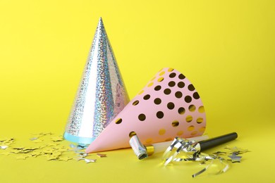 Photo of Beautiful party hats and other festive decor on yellow background