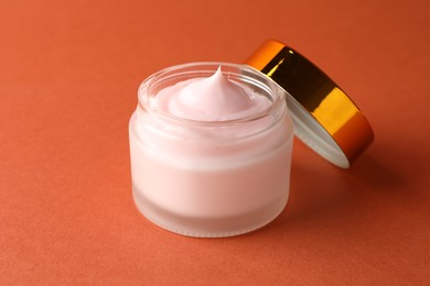 Photo of Jar of moisturizing body cream on orange background, closeup