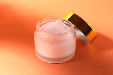 Photo of Jar of moisturizing body cream on orange background, closeup
