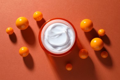 Photo of Jar of moisturizing body cream and balls on orange background, flat lay