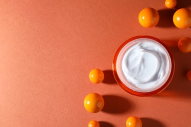 Photo of Jar of moisturizing body cream and balls on orange background, flat lay. Space for text