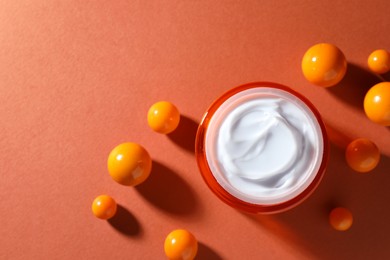 Photo of Jar of moisturizing body cream and balls on orange background, flat lay. Space for text