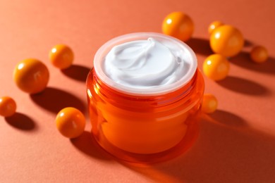 Photo of Jar of moisturizing body cream and balls on orange background, closeup
