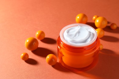 Photo of Jar of moisturizing body cream and balls on orange background, closeup