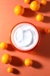 Photo of Jar of moisturizing body cream and balls on orange background, flat lay