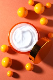 Photo of Jar of moisturizing body cream and balls on orange background, flat lay