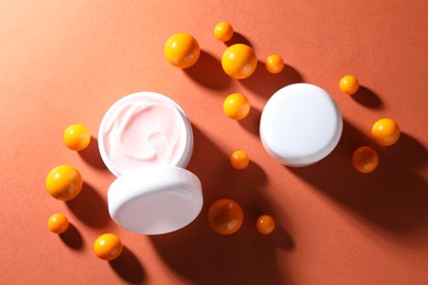 Photo of Jars of moisturizing body cream and balls on orange background, flat lay