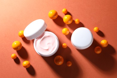 Photo of Jars of moisturizing body cream and balls on orange background, flat lay