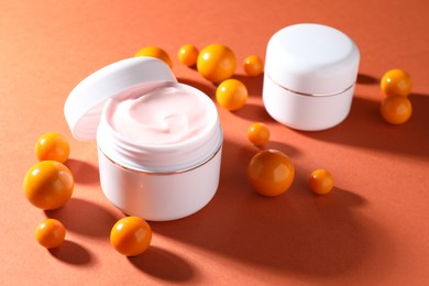 Photo of Jars of moisturizing body cream and balls on orange background, closeup