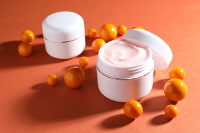 Photo of Jars of moisturizing body cream and balls on orange background, closeup