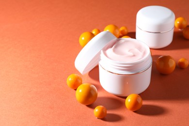 Photo of Jars of moisturizing body cream and balls on orange background, closeup. Space for text