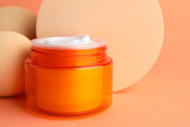 Photo of Stylish presentation of moisturizing body cream in jar on orange background, closeup. Space for text