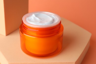Photo of Stylish presentation of moisturizing body cream in jar on orange background, closeup