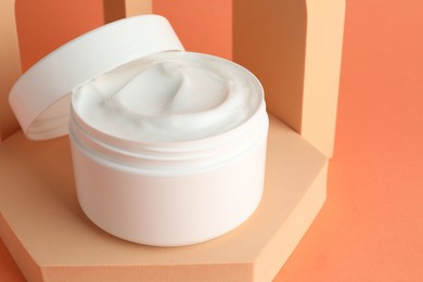 Photo of Stylish presentation of moisturizing body cream in jar on orange background, closeup. Space for text