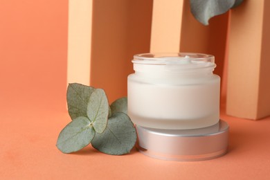 Photo of Stylish presentation of moisturizing body cream in jar on orange background, closeup