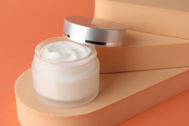 Photo of Stylish presentation of moisturizing body cream in jar on orange background, closeup