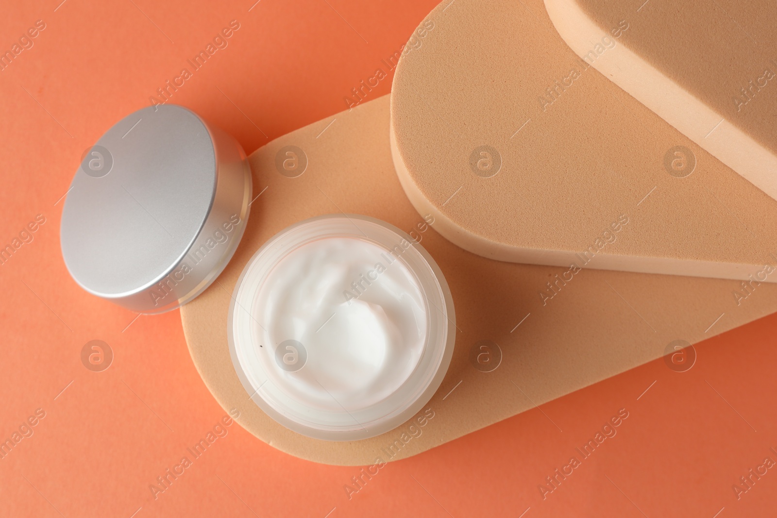 Stylish presentation of moisturizing body cream in jar on orange background, top view Photo of Stylish presentation of moisturizing body cream in jar on orange background, top view