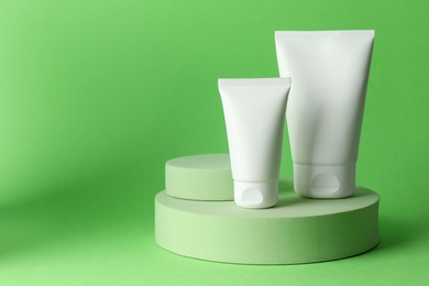Photo of Stylish presentation of moisturizing body cream in tubes on light green background, closeup. Space for text