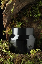 Photo of Jar of moisturizing body cream on tree bark with plants, closeup
