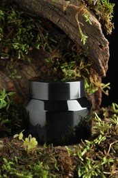 Photo of Jar of moisturizing body cream on tree bark with plants, closeup