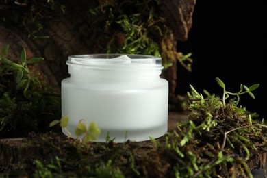 Photo of Jar of moisturizing body cream on tree bark with plants, closeup