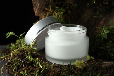 Photo of Jar of moisturizing body cream on tree bark with plants, closeup