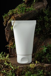 Photo of Jar of moisturizing body cream on tree bark with plants, closeup