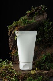 Photo of Jar of moisturizing body cream on tree bark with plants, closeup