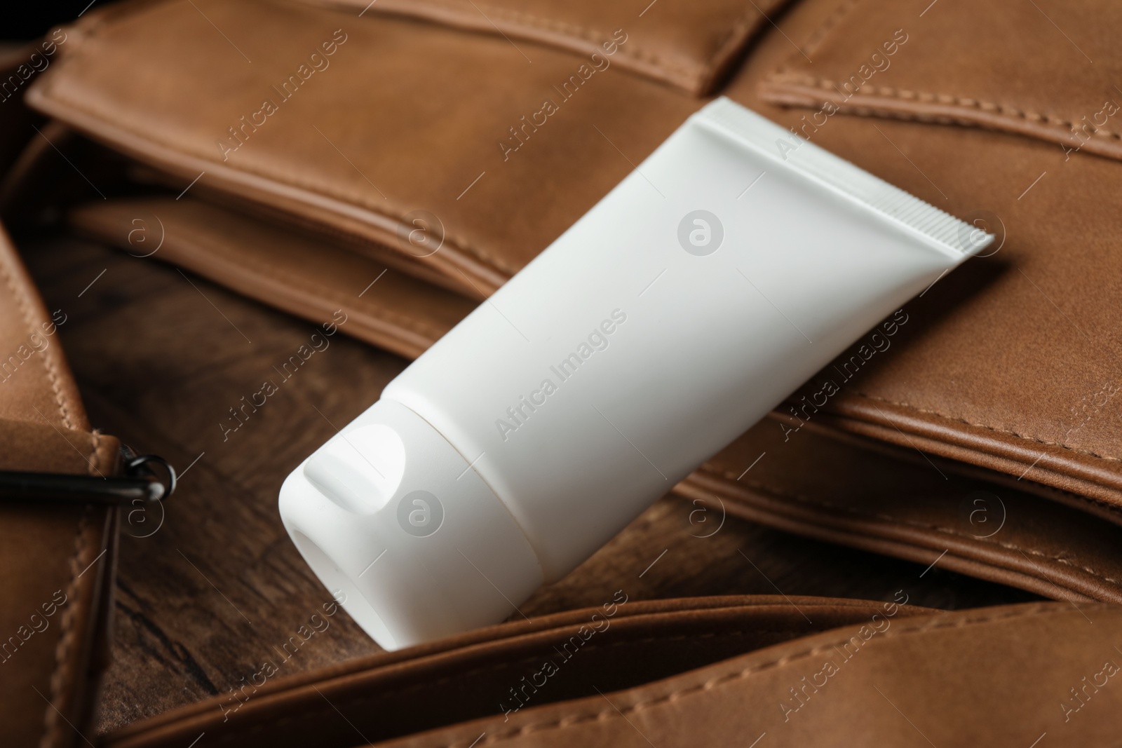 Tube of moisturizing body cream and leather bag on wooden table, closeup Photo of Tube of moisturizing body cream and leather bag on wooden table, closeup