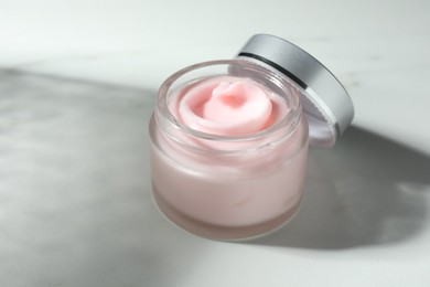 Photo of Jar of moisturizing body cream on white table, closeup. Space for text