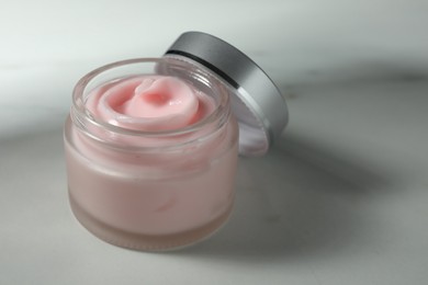 Photo of Jar of moisturizing body cream on white table, closeup