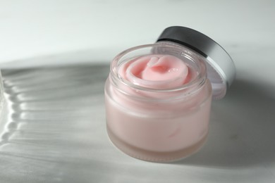 Photo of Jar of moisturizing body cream on white table, closeup