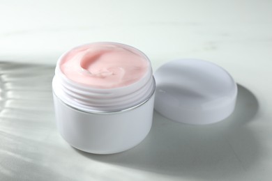 Photo of Jar of moisturizing body cream on white table, closeup
