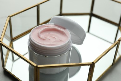 Photo of Jar of moisturizing body cream and glass tray on white table, closeup