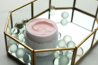 Photo of Jar of moisturizing body cream and glass tray on white table, closeup