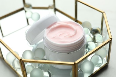 Photo of Jar of moisturizing body cream and glass tray on white table, closeup