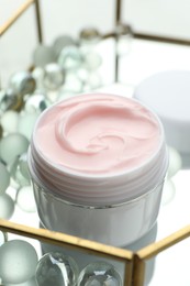 Photo of Jar of moisturizing body cream and glass tray on white table, closeup