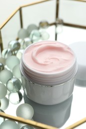 Photo of Jar of moisturizing body cream and glass tray on white table, closeup