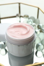 Photo of Jar of moisturizing body cream and glass tray on white table, closeup