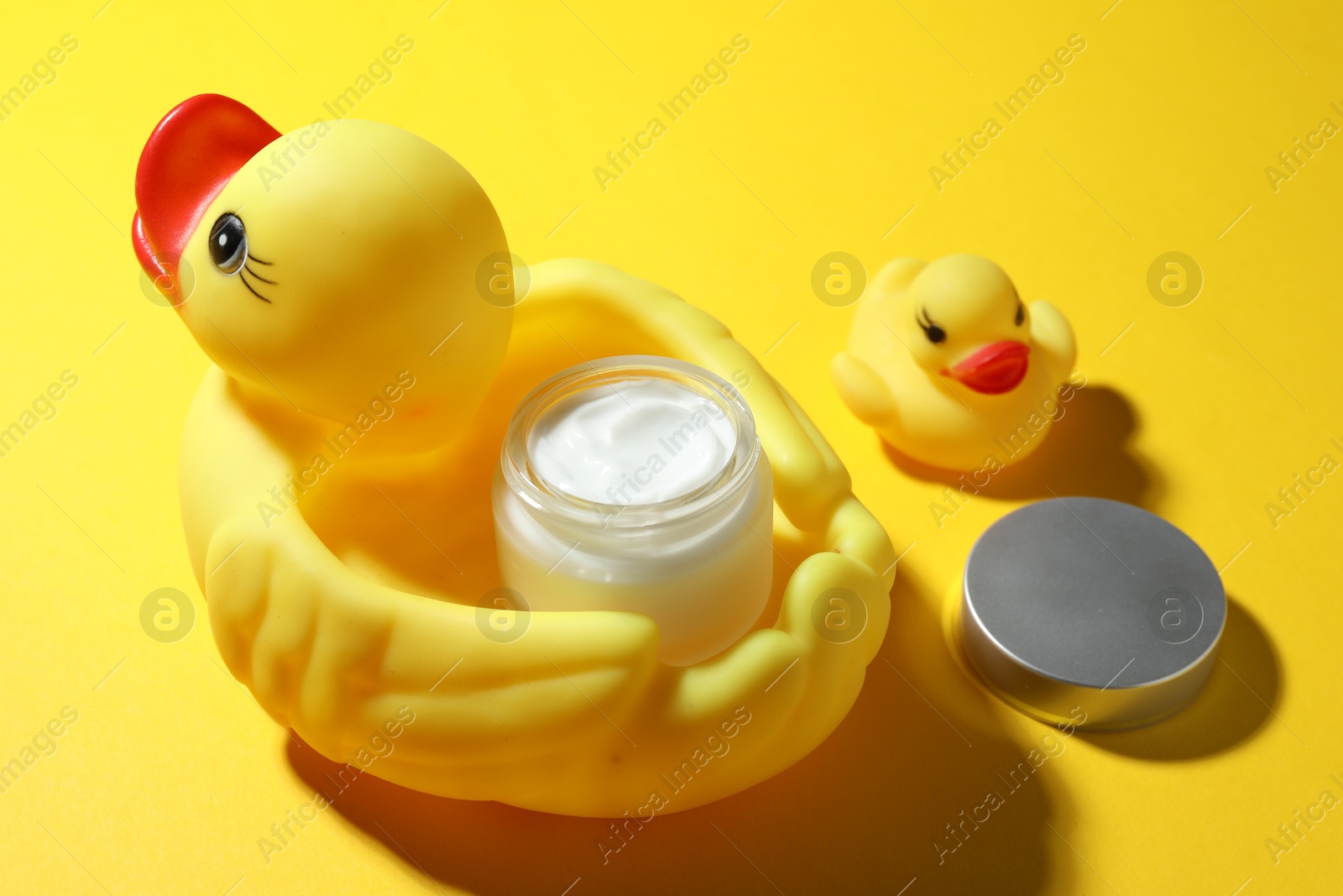 Jar of moisturizing body cream and rubber ducks on yellow background, closeup Photo of Jar of moisturizing body cream and rubber ducks on yellow background, closeup