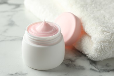 Photo of Jar of moisturizing body cream on white marble table, closeup