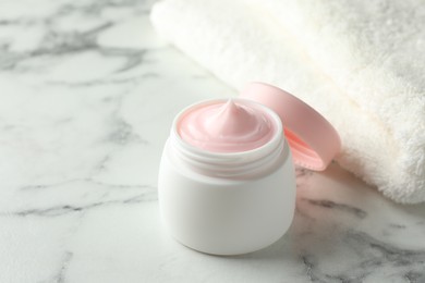 Photo of Jar of moisturizing body cream on white marble table, closeup. Space for text