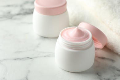 Photo of Jar of moisturizing body cream on white marble table, closeup. Space for text
