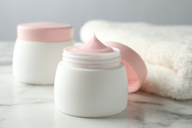 Photo of Jar of moisturizing body cream on white marble table, closeup