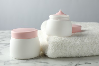Photo of Jar of moisturizing body cream on white marble table, closeup