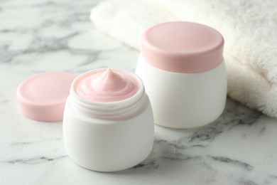 Photo of Jar of moisturizing body cream on white marble table, closeup
